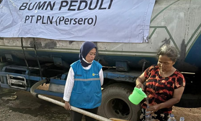 Relawan PLN terlihat sedang mengalirkan air bersih dari truk ke sebuah box penampungan.