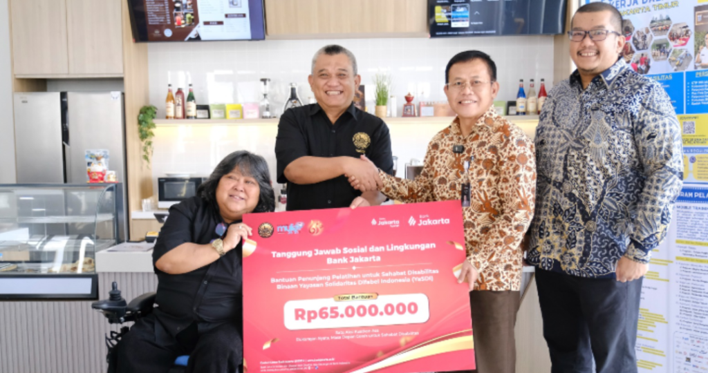 Direktur Kepatuhan Bank Jakarta Ateng Rivai (kiri) didampingi Sekretaris Perusahaan Arie Rinaldi menyerahkan bantuan penunjang pelatihan kepada Ketua Pembina Yayasan Solidaritas Difabel Indonesia Suty Karno (kanan) di Pusat Pelatihan Kerja Daerah Jakarta Timur sebagai bagian rangkaian HUT ke-65 Bank Jakarta yang menitikberatkan pada pemberdayaan difabel dan inklusi sosial. Dok: Istimewa.