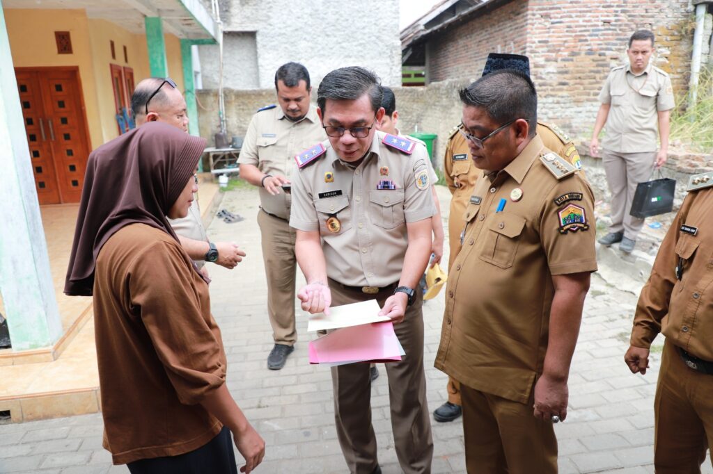 Kepala Kanwil BPN Provinsi Banten, Harison Mocodompis, menyerahkan sertipikat PTSL secara door to door kepada warga di Kelurahan Kalodran, Kota Serang. Dok: BPN Banten.