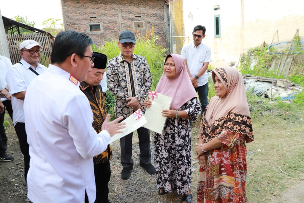 Kepala Kanwil BPN Provinsi Banten Harison Mocodompis menyerahkan sertipikat tanah secara langsung kepada warga di Desa Toyomerto. Dok: Istimewa.